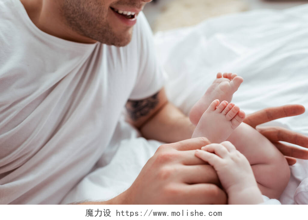 笑着的父亲摸着可爱男婴的小腿笑着的父亲摸着可爱男婴的小腿的剪影 